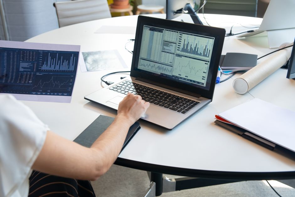 Osoba procjenjuje financijske grafikone na laptopu u modernom uredu